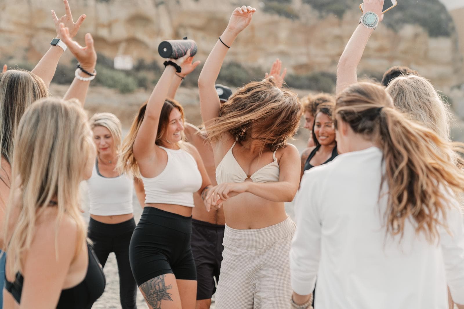 A group of friends dancing together on the beach at golden hour