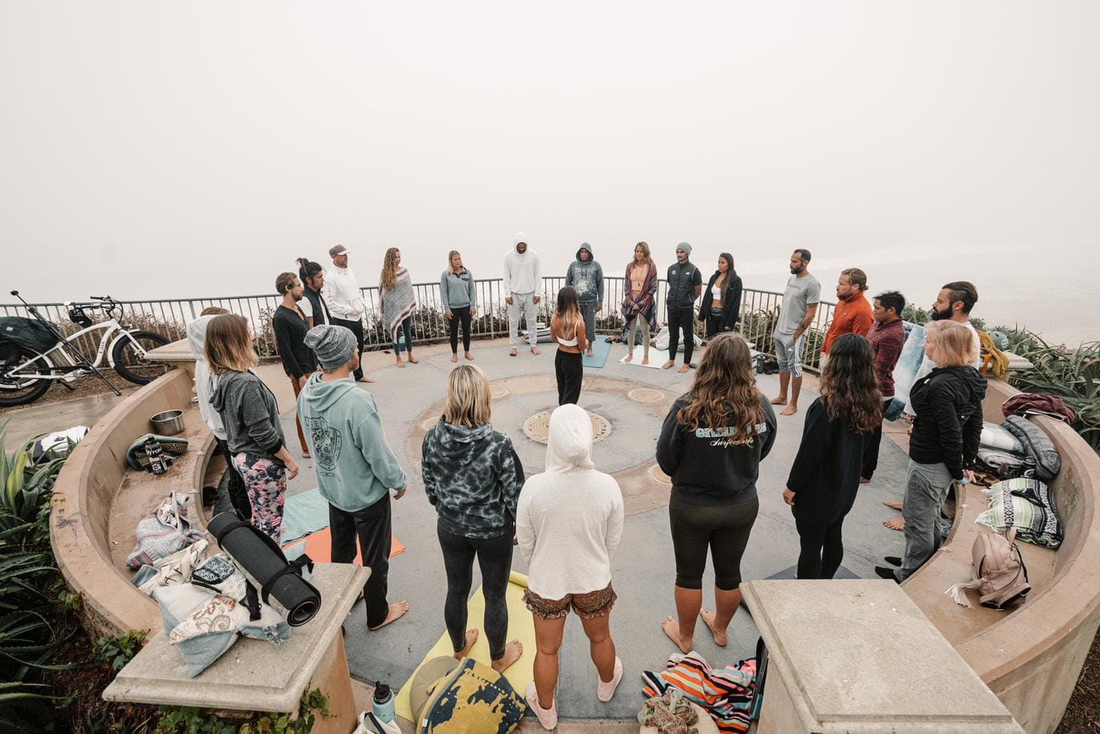 A circle of friends sitting close together on the floor, eyes shut, breathing together