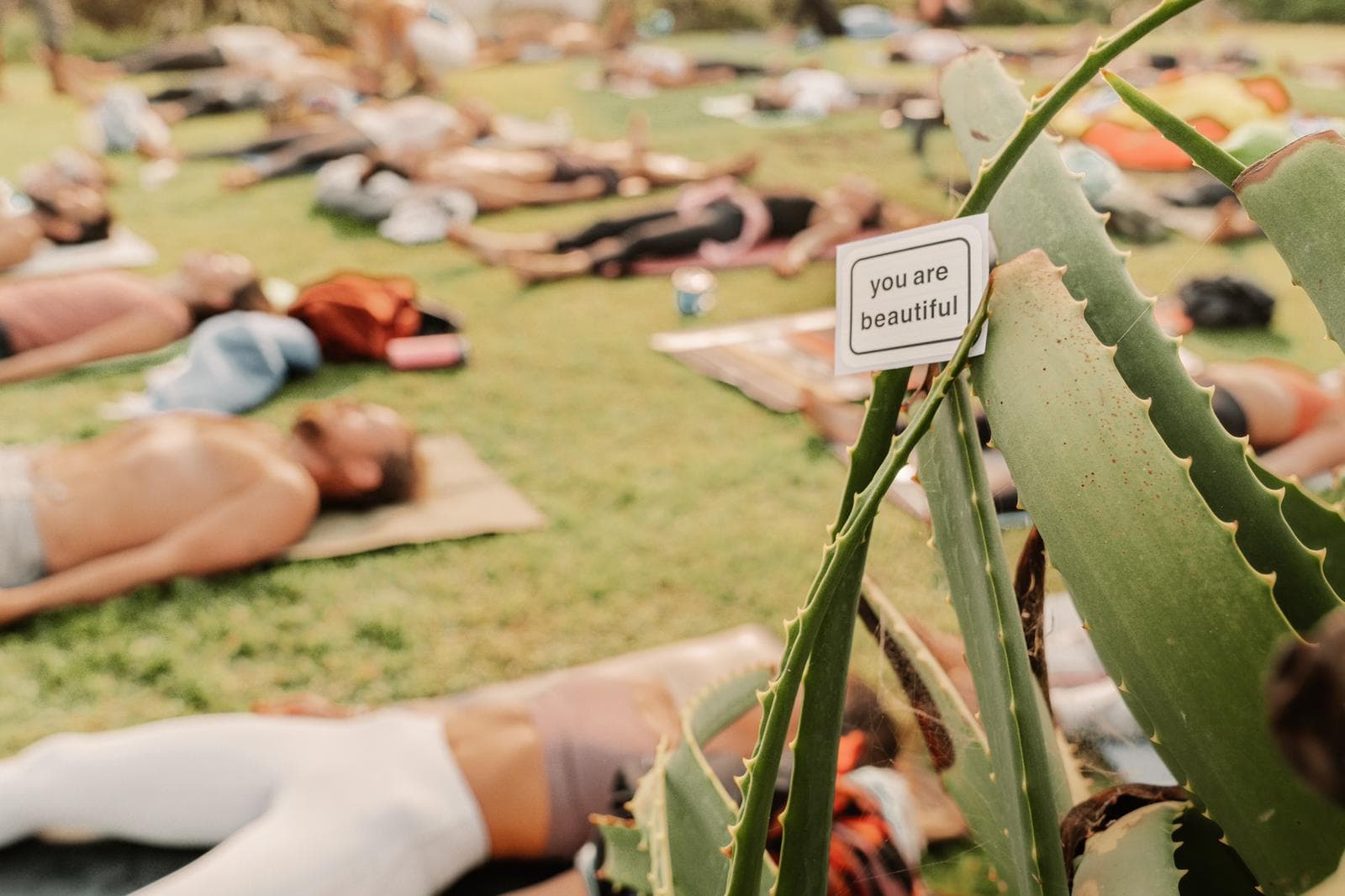 A Frequency member resting in savasana beside a hand-lettered “you are beautiful” sign