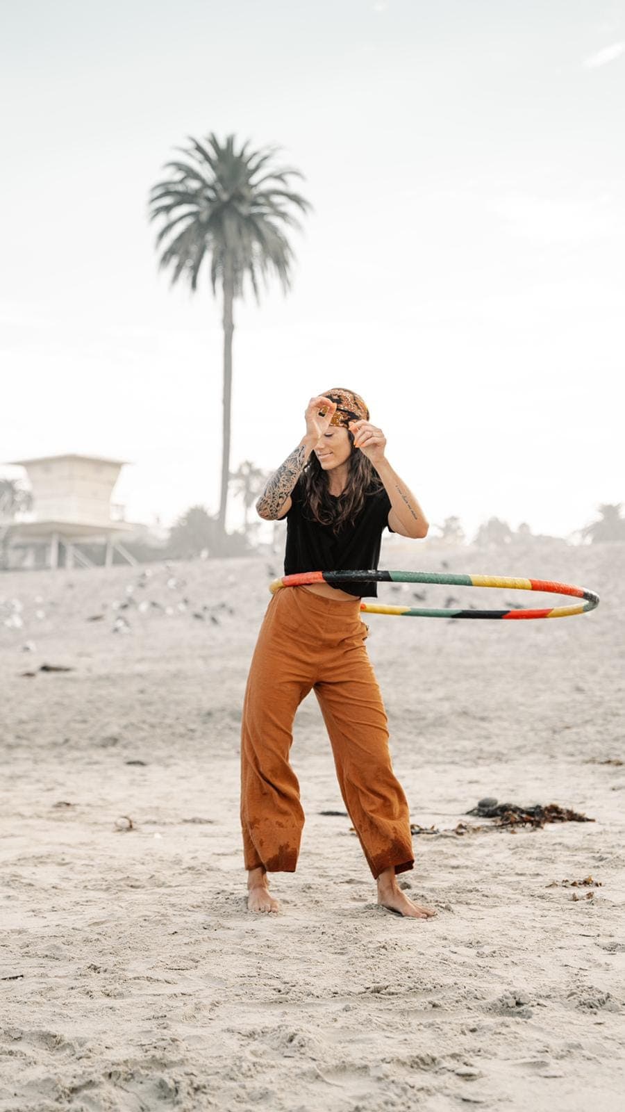 A woman hula-hooping on the beach