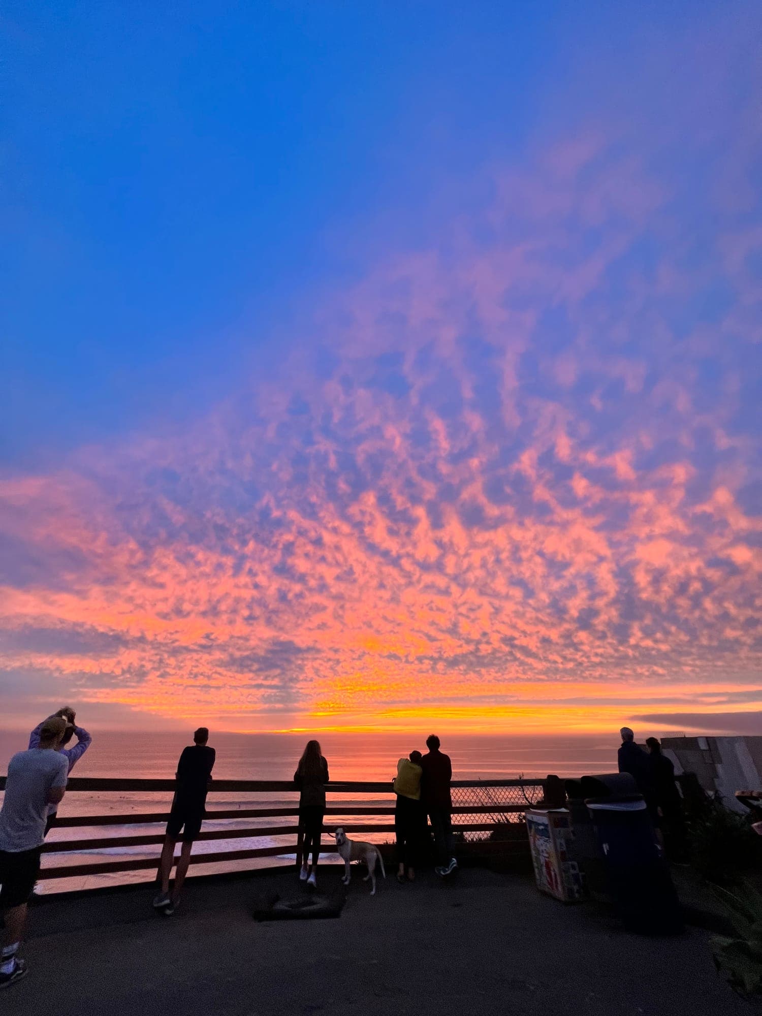 A few people watching the sunset together from a quiet hillside
